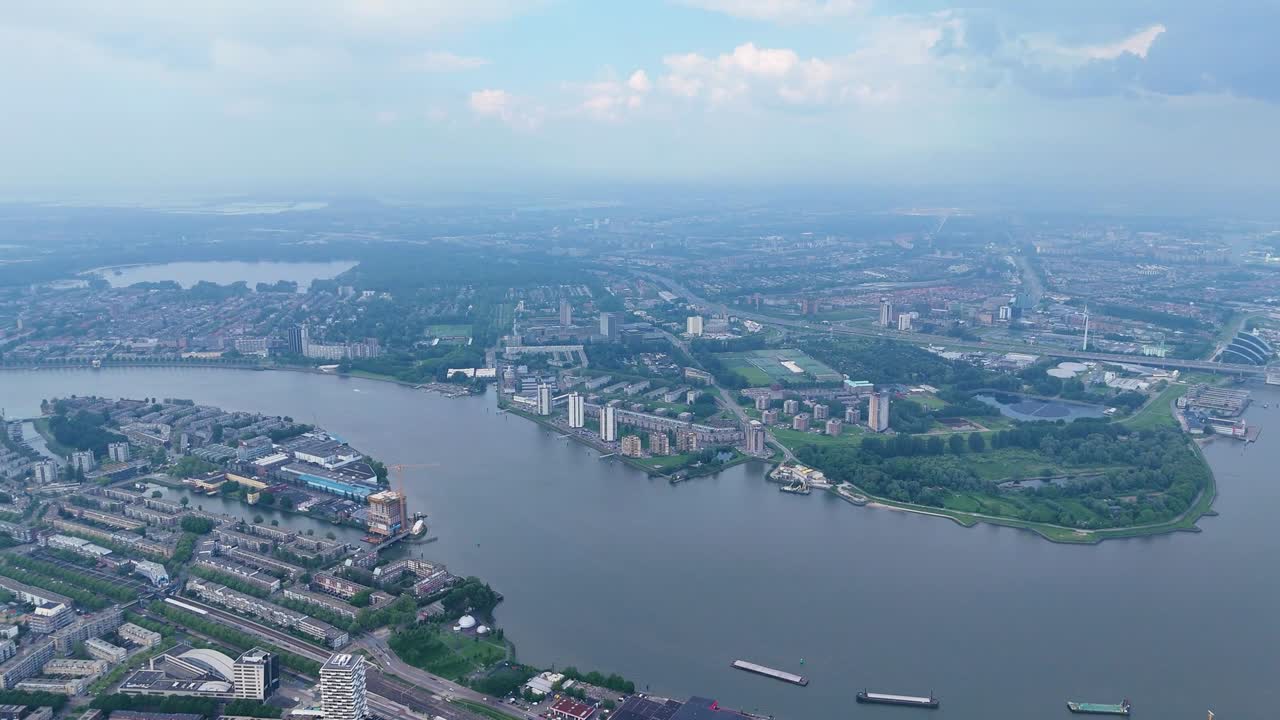 Aerial panoramic view of Nijmegen city showing Waal River, arched bridge, and stadium surrounded by modern buildings and greenery under cloudy blue sky capturing scenic urban Dutch landscape