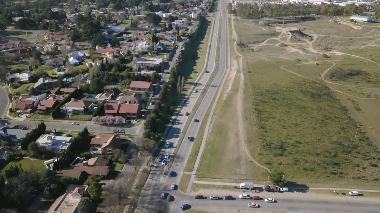 Ripresa aerea con drone di un'autostrada con auto in transito e sobborghi ai lati.