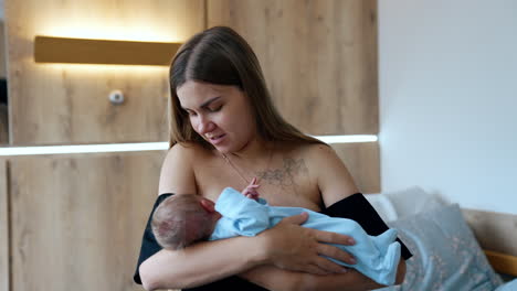 long-haired caucasian mother waving a newborn in hands. happy woman canoodling her baby.