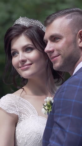 slow motion wedding couple hugs smiling and pretty bride in white lacy dress blows on open shoulder in park