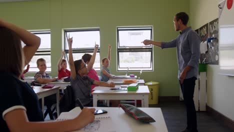 group of kids raising their hands in the class