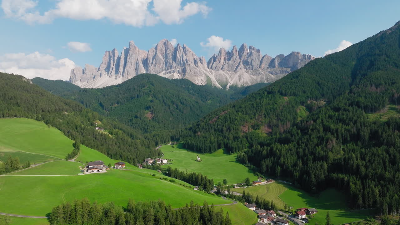 Establishing of Church of St. John and forest valley with towering Dolomite cliffs beyond