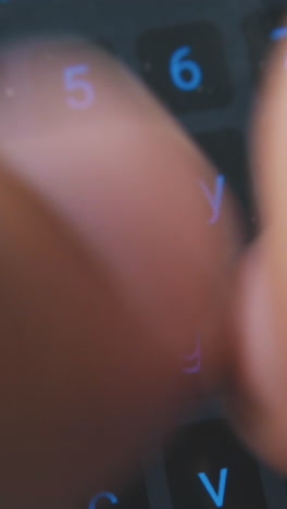 young man types text on touch pad screen keyboard on modern mobile phone extreme close view