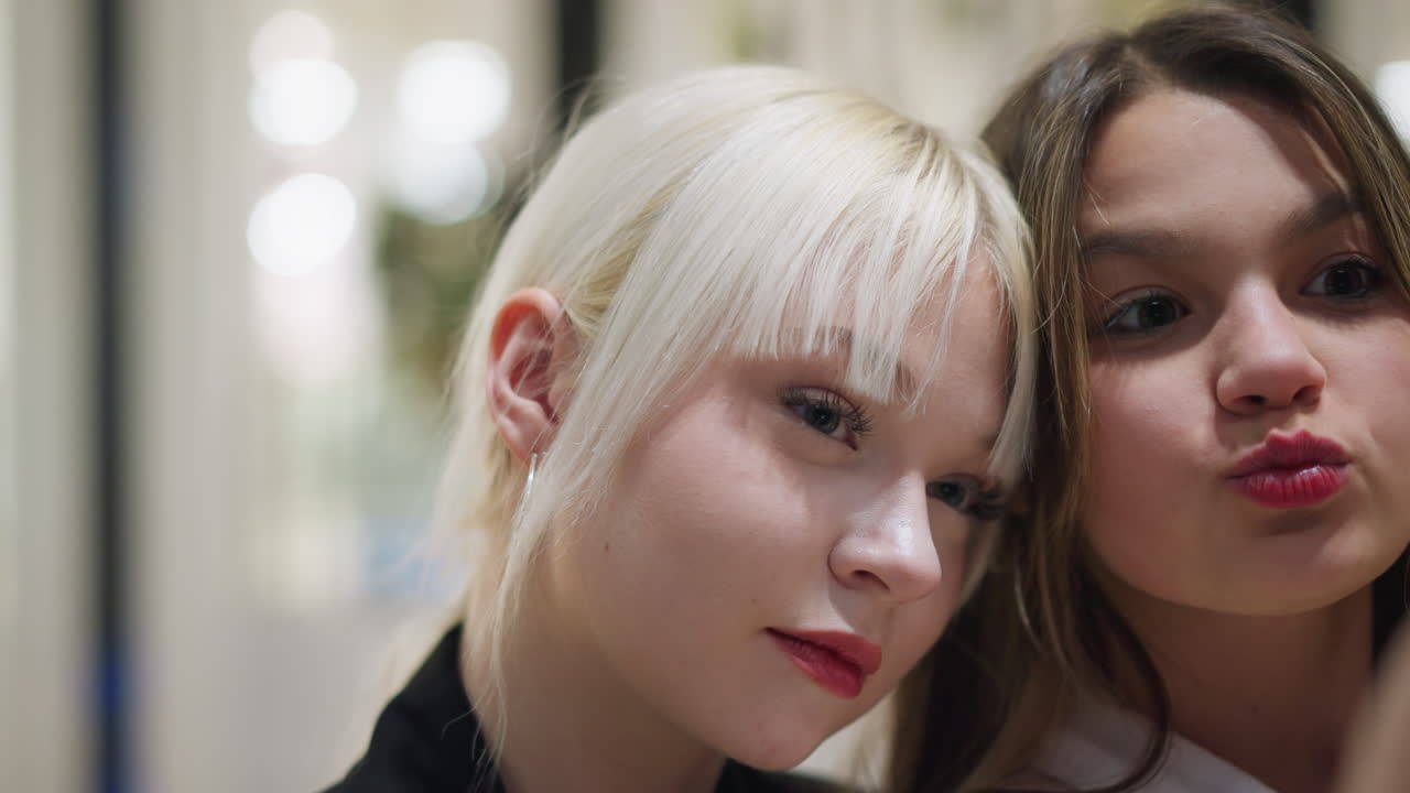Two siblings smiling while making video on smartphone indoors with close friendly expressions capturing playful joyful moment that reflects family bonding youth lifestyle and fun digital culture