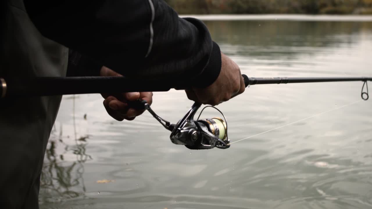 Close-up pemancing menggulung reel joran pancing dalam gerakan super lambat