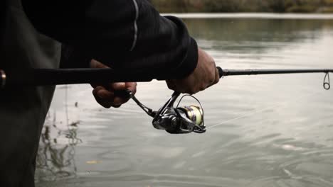 close up fisherman winding reel reeling in fishing rod super slow motion