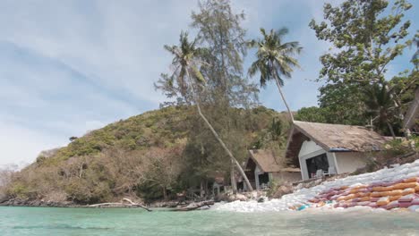 koh hey resort shacks with sandbag barrier to prevent coastal erosion in thailand - wide survey shot