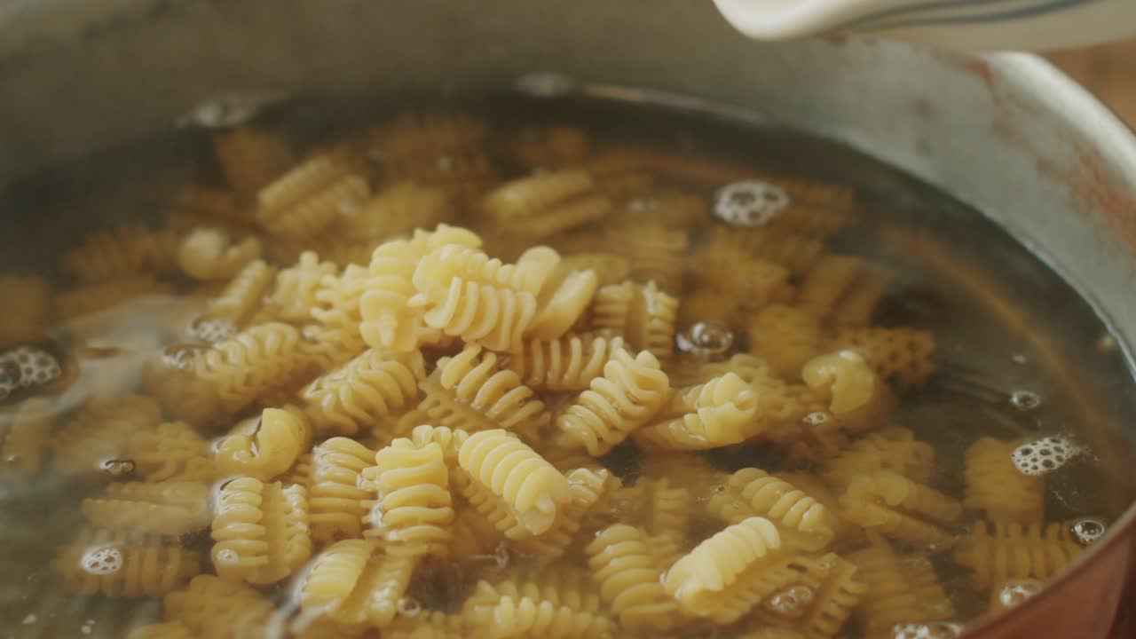 mujer sin rostro preparando pasta en la cocina