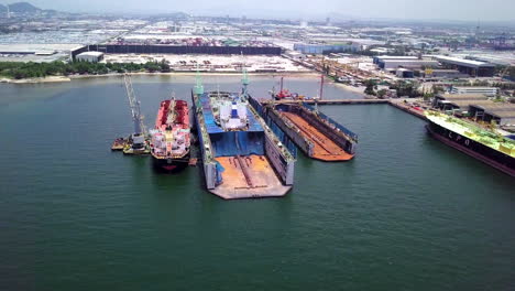 aerial view of logistics concept a cargo ship being retrofit, repair and services on a floating dry dock off the coast at laem chabang dockyard in chonburi province, thailand