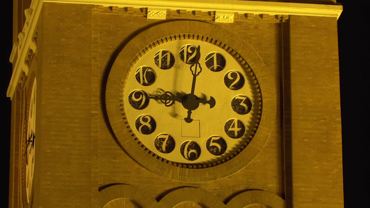A close-up of the huge clock on the tower of Szeged Cathedral as the hand changes minutes at night in Hungary