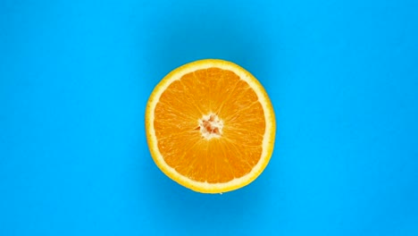 top view: half of an orange rotates on a blue surface - fast motion