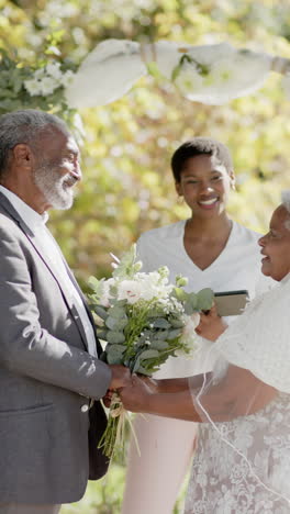 slow-motion vertical video of a black woman officiating a senior biracial couple's wedding
