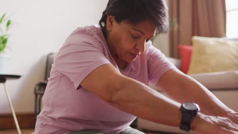 Ältere-Biraziale-Frau-Praktiziert-Yoga-Und-Stretching-Im-Wohnzimmer