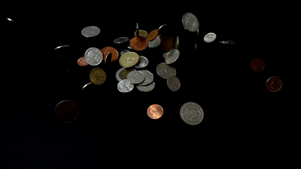 Coins fall on a black background. Slow motion
