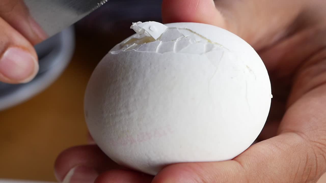 Close-up of Hands Cracking and Peeling a Hard-Boiled Egg