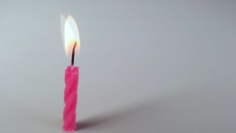 pink birthday candle melting on grey background time lapse