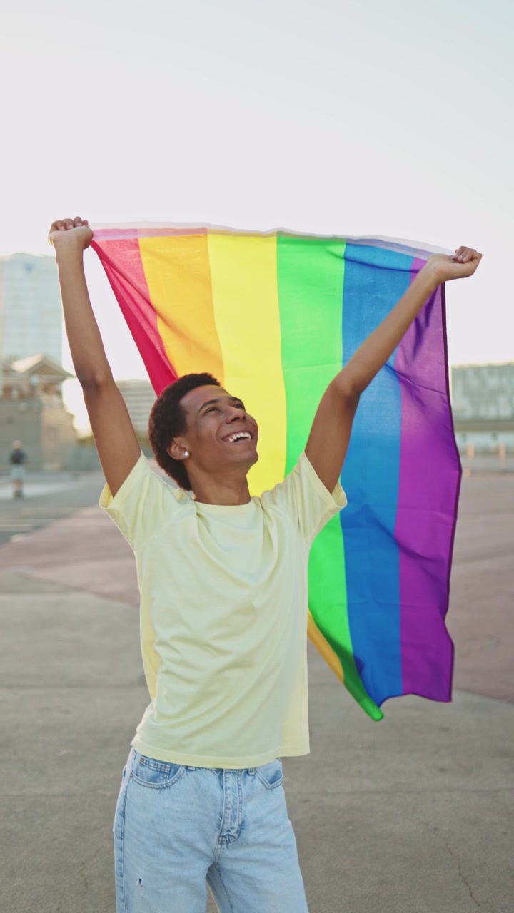 Happy Young Man Holding Rainbow Flag Outdoors