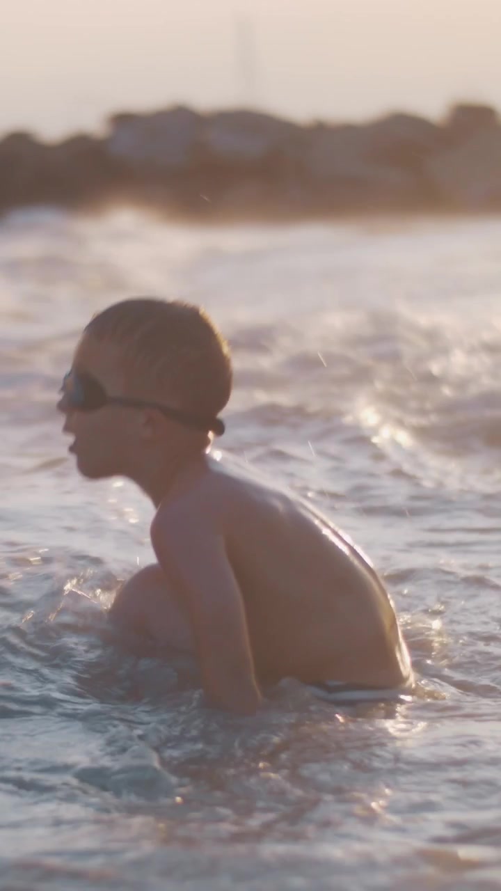 Child bathing in the sea near shore at sunset