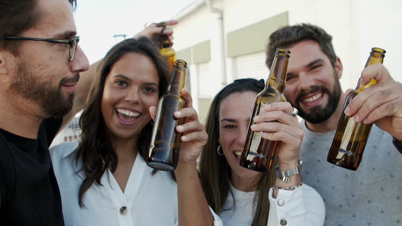 amigos sonrientes sosteniendo botellas de cerveza y mirando a la cámara