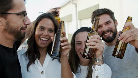 smiling friends holding beer bottles and looking at camera