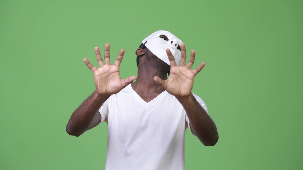 Young African man wearing white mask and trying to scare