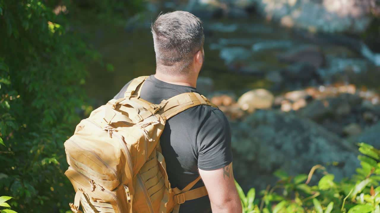 excursionista masculino de pie junto al río de la selva mirando a la naturaleza, caminata en el bosque salvaje día caluroso de verano, actividad al aire libre y concepto de viaje