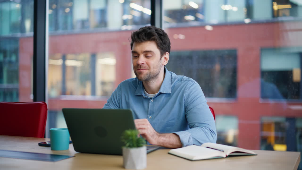 Smiling creator looking laptop sitting by office window closeup. Inspired man