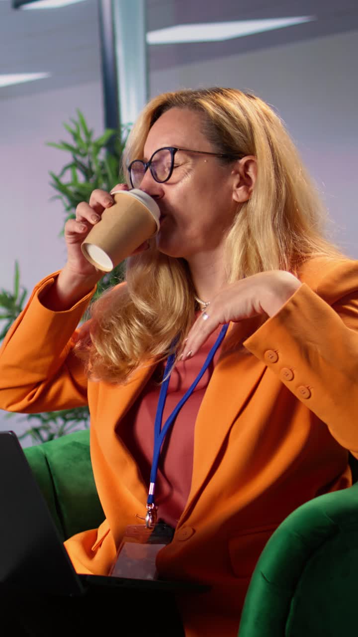 Blond kvinde gaber og drikker kaffe, mens hun arbejder