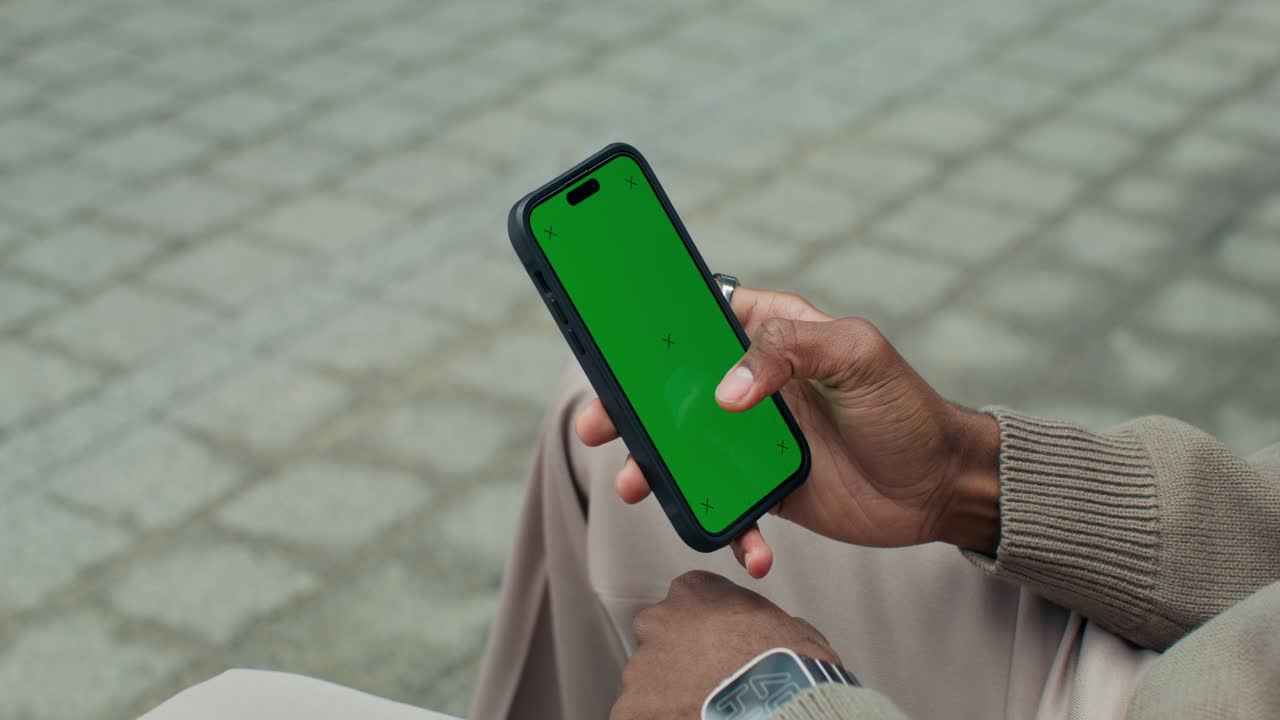 Person holder en smartphone med grøn skærm udendørs