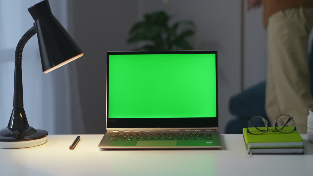 la persona ha terminato il lavoro in ufficio a casa sta spegnendo le luci nella stanza e chiudendo il portatile con closeup sullo schermo verde sul tavolo di lavoro per il lavoro remoto nell'appartamento