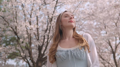 mujer cubre su cara con la mano mientras camina en el parque con flores de cerezo en un día soleado en seúl, corea del sur