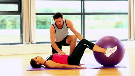 mujer delgada y deportiva levantando una pelota de fitness con sus piernas