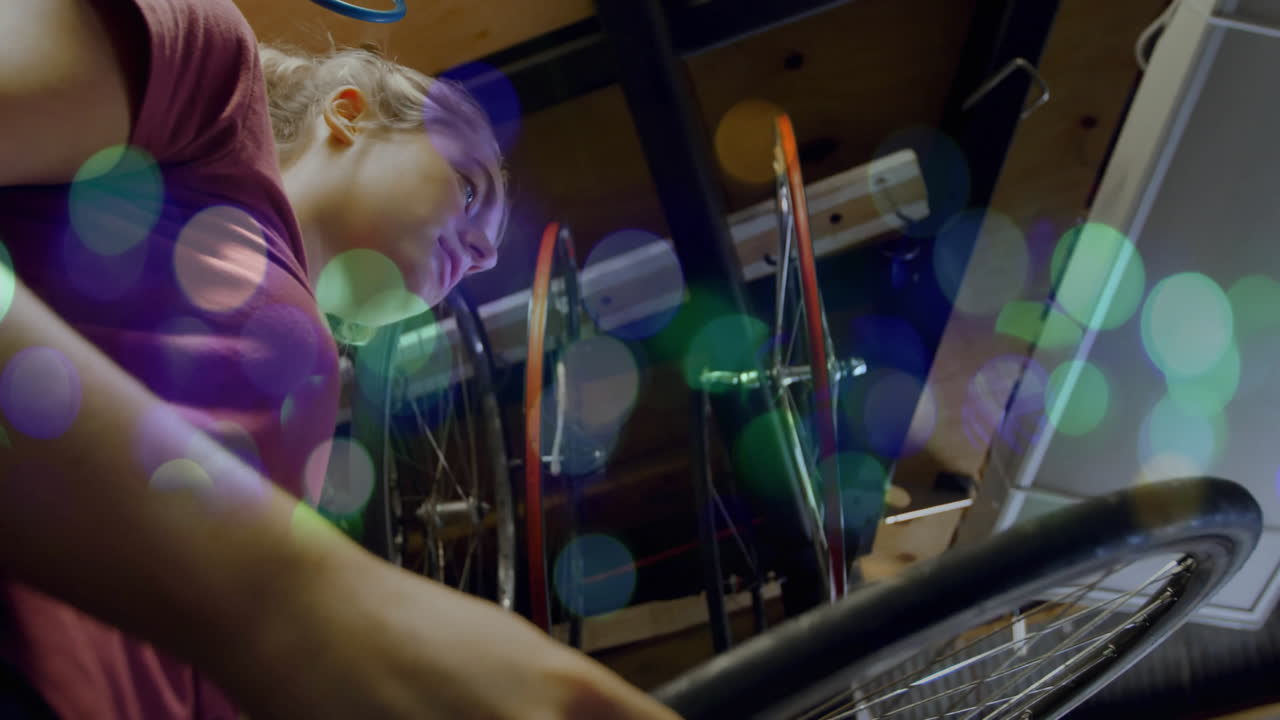woman leaning over workbench, inspecting bicycle wiring in tech lab, showing animated bokeh lights