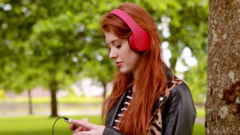 Pretty-redhead-listening-to-music-in-the-park-