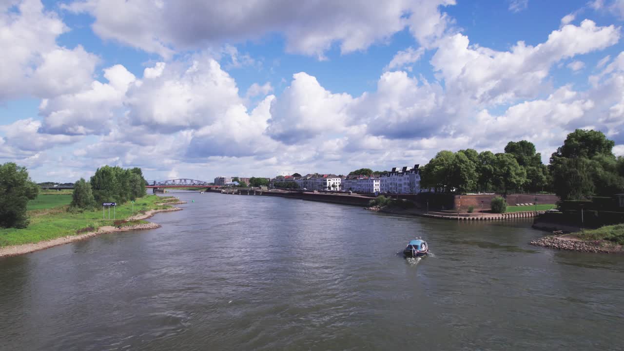 Recreational boat on river IJssel sailing towards leisure port Gelre in Zutphen. Aerial inland shipping and tourism waterway infrastructure concept