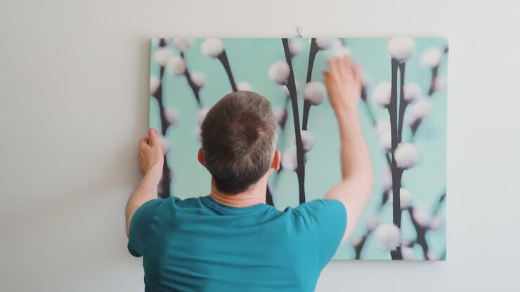 Uomo che appende un quadro al muro