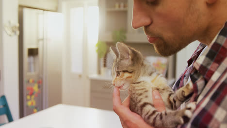 smiling young man playing with his pet cat in the kitchen 4k 4k
