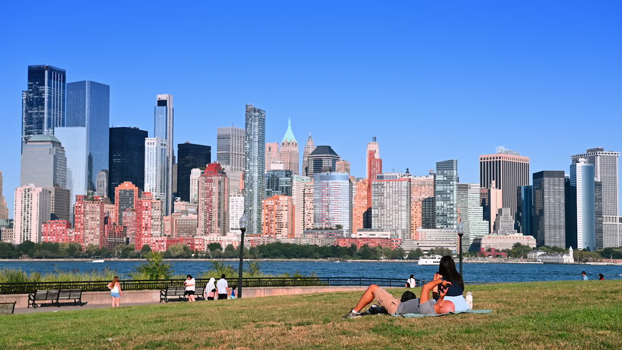 New Jersey, USA, 19 August 2025: People walk, sit and take pictures at the quay in Jersey City, USA. Relaxed day at near the river on sunny day. Iconic Manhattan skyline at backdrop
