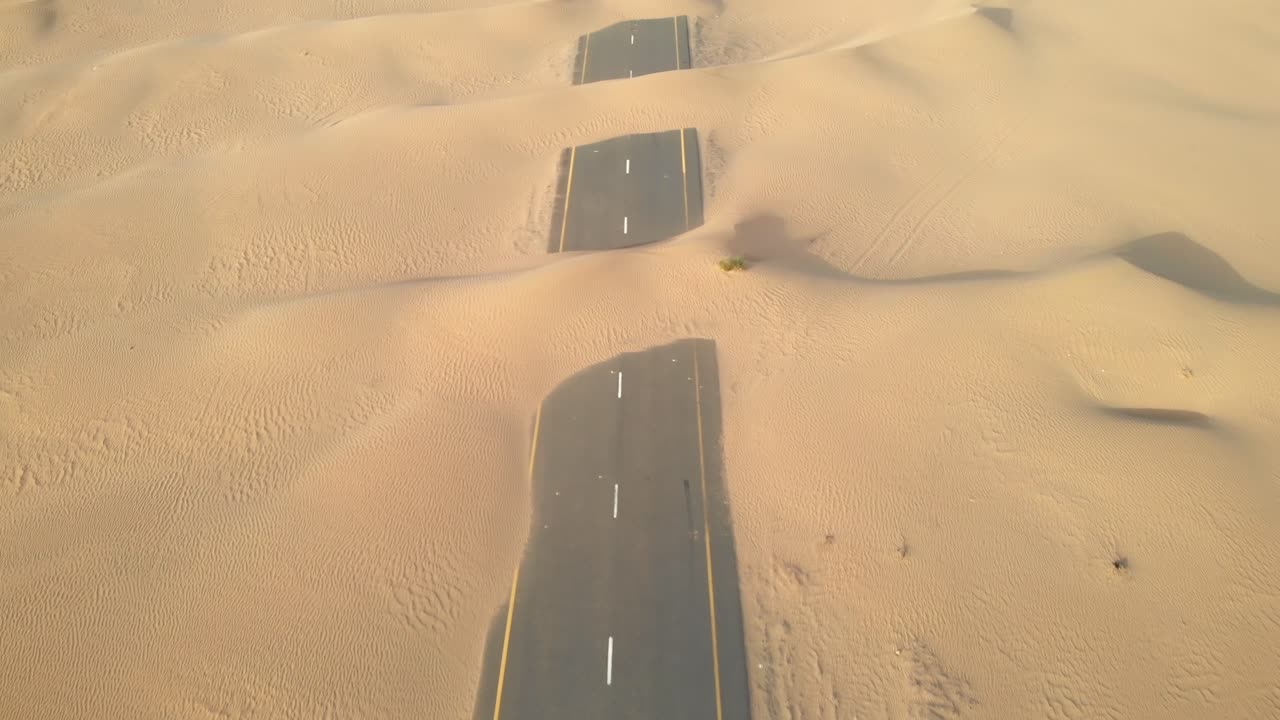 Aerial view from drone of abandoned desert roads covered with sand dunes in Dubai, United Arab Emirates