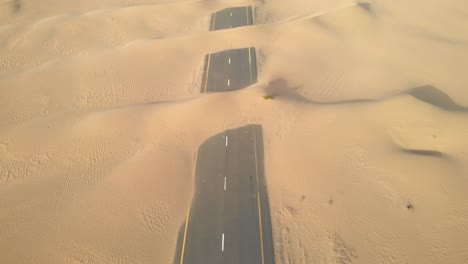 aerial view from drone of abandoned desert roads covered with sand dunes in dubai, united arab emirates