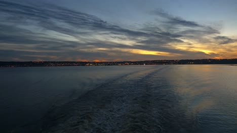 navegando desde la baie en el río saguenay al atardecer con las luces de la ciudad al fondo
