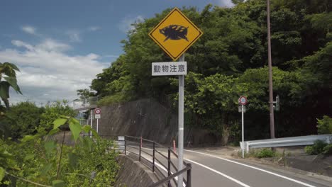 Wild-Boar-Warning-Sign-on-Rural-Road-in-Japan,-Tilt-Shot