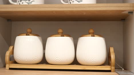 white ceramic spice jars with wooden lids on a bamboo tray