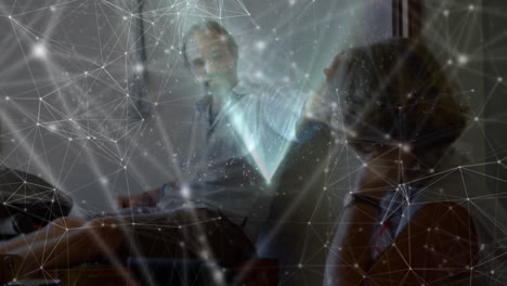 Animation of glowing network of connections floating over work colleagues in discussion