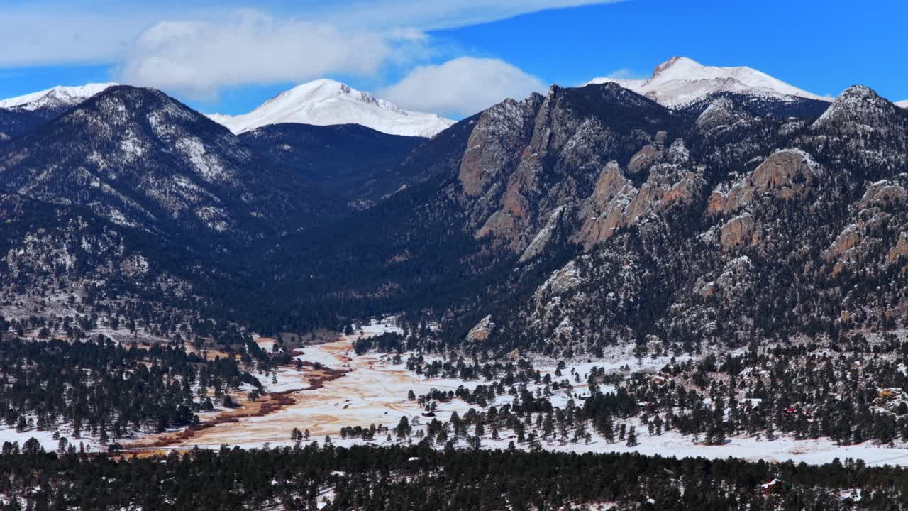 Estes Park, Parco Nazionale delle Montagne Rocciose, città di montagna, Lumpy Ridge, formazione rocciosa Twin Owls, Catena del Mummy, Colorado, paesaggio di valle ripreso da drone aereo, tramonto, neve fresca, nuvole, cielo blu, soleggiato, movimento panoramico a sinistra.