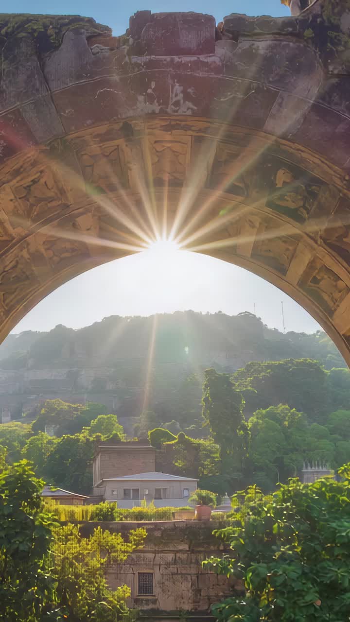 Vertical video: Sunlight shifting behind stone arch at terrace, arch revealing coffers and pots