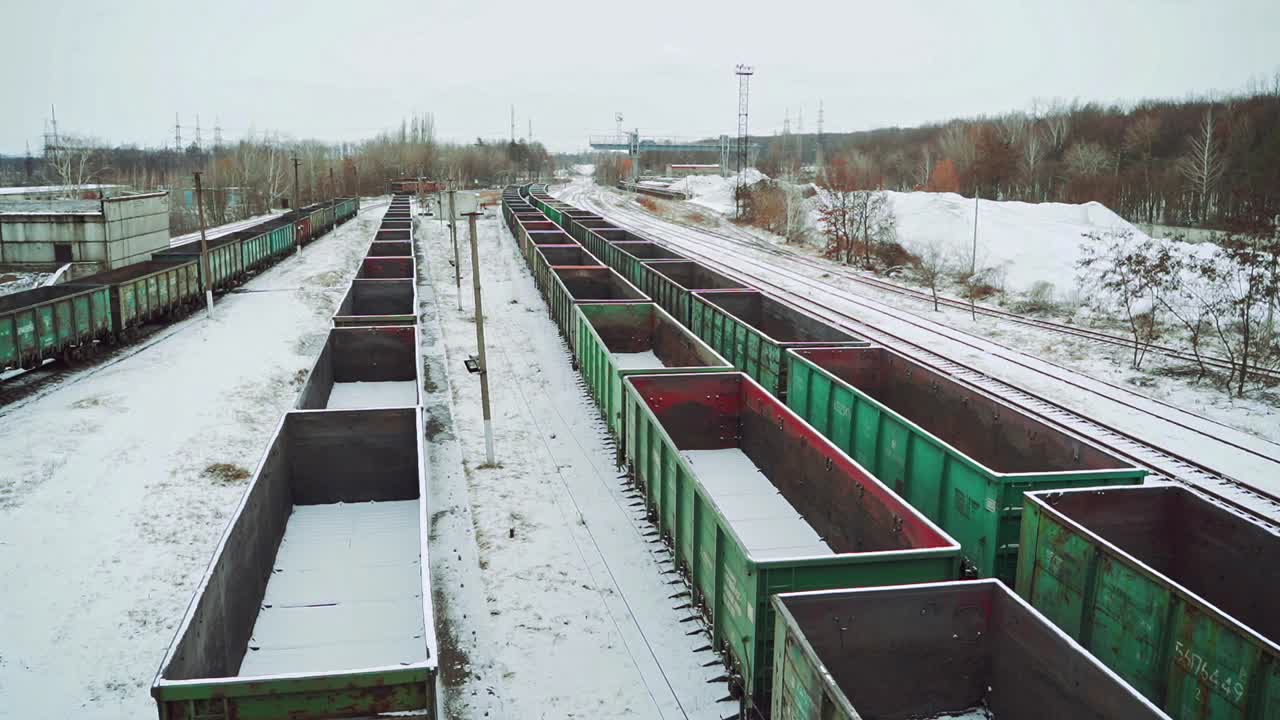 Empty shipping containers are located at an abandoned railway station in the countryside against the background of snow and forest. Aerial view.