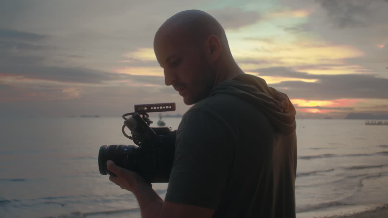 Videographer filming sunset over the beach