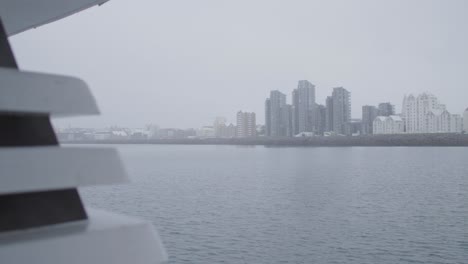 Looking-at-apartment-buildings-on-shore-of-Reykjavik-in-Iceland-from-yacht,-cloudy-day