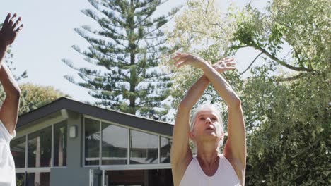 focused diverse seniors having pilates class in sunny garden, unaltered, in slow motion